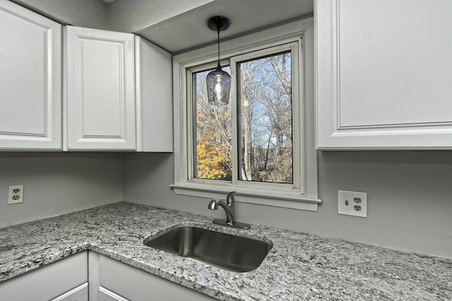 kitchen featuring pendant lighting, sink, a healthy amount of sunlight, and white cabinets