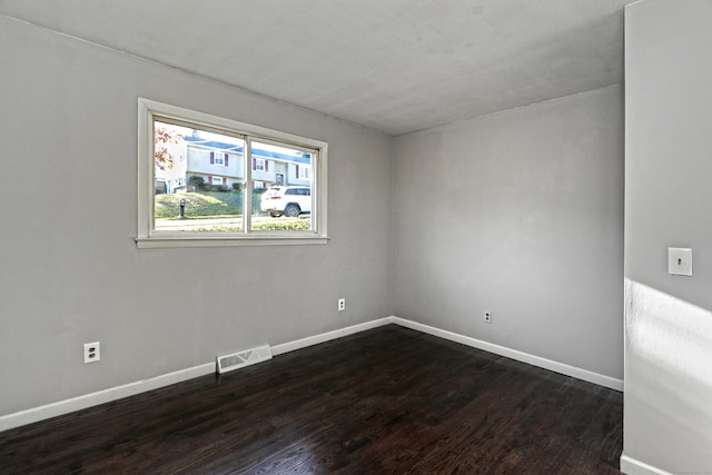 empty room with dark wood-style floors, baseboards, and visible vents