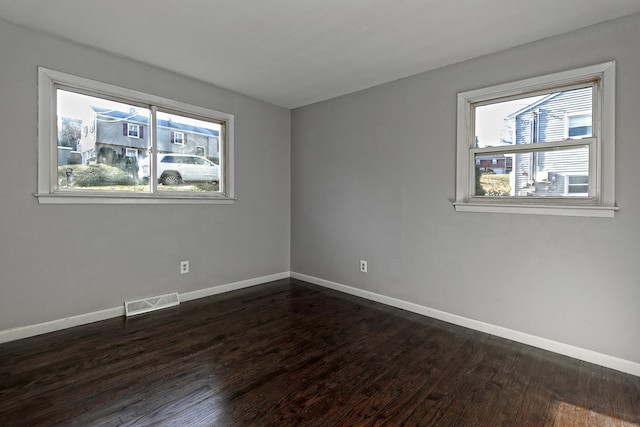 unfurnished room with plenty of natural light, dark wood finished floors, and baseboards