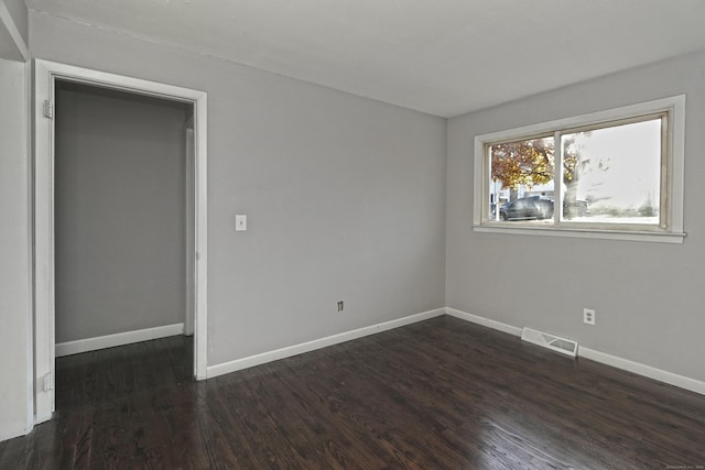 unfurnished bedroom with baseboards, visible vents, and dark wood-style flooring