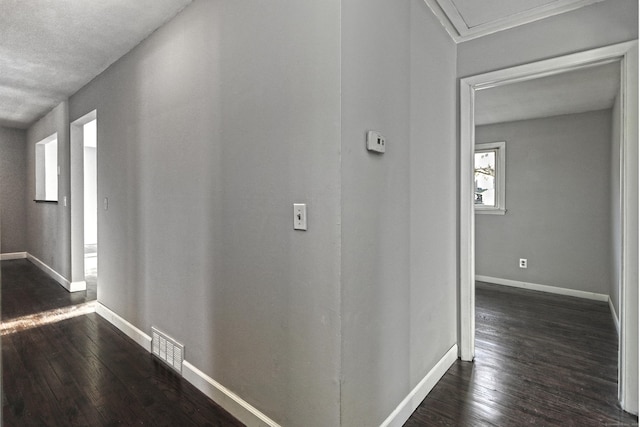 corridor featuring dark wood-style floors, visible vents, and baseboards