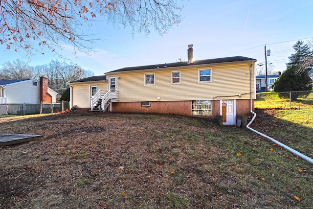 rear view of house featuring entry steps and fence