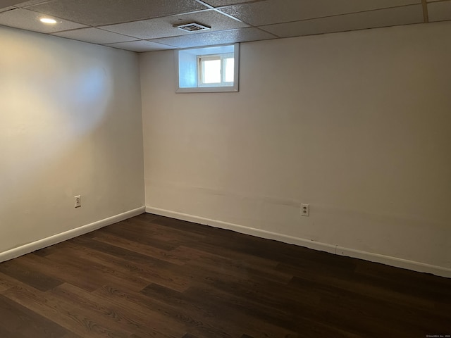 basement with dark wood-type flooring and a paneled ceiling