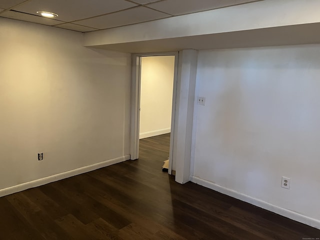 empty room with dark hardwood / wood-style flooring and a paneled ceiling