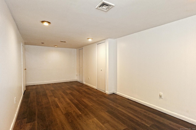 spare room featuring dark wood finished floors, visible vents, and baseboards