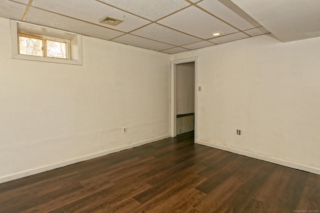 below grade area featuring a paneled ceiling, dark wood-style flooring, visible vents, and baseboards