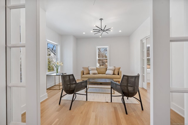 living room featuring an inviting chandelier, a healthy amount of sunlight, and light wood-type flooring