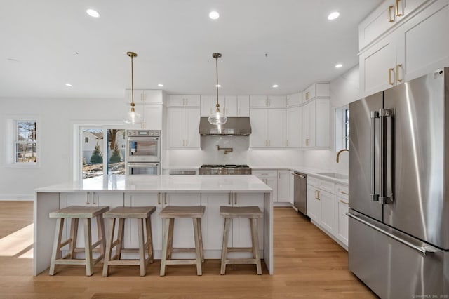 kitchen with a kitchen island, appliances with stainless steel finishes, pendant lighting, tasteful backsplash, and white cabinetry