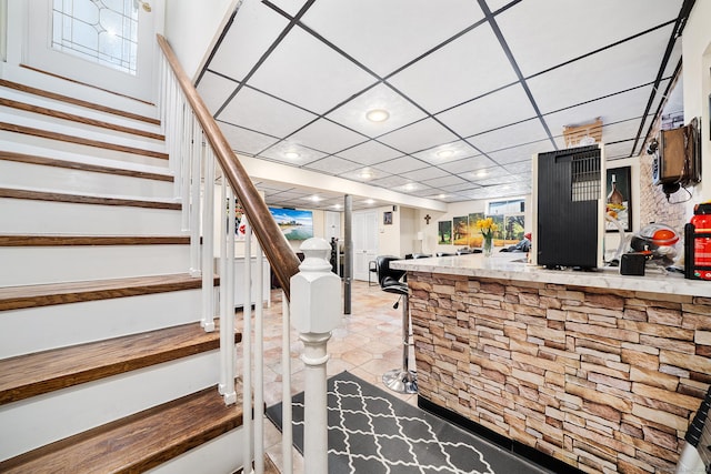 stairway featuring bar area and a drop ceiling