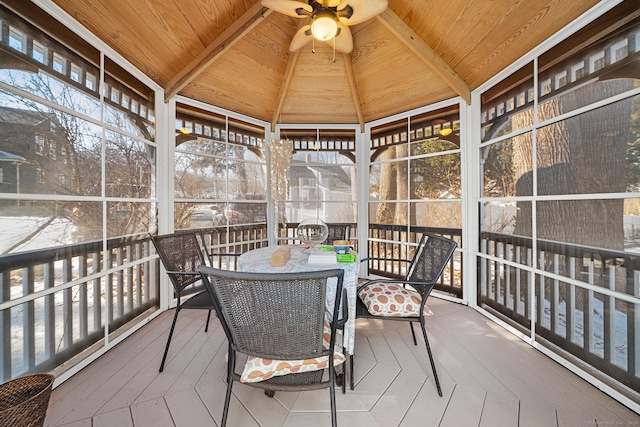 sunroom / solarium featuring vaulted ceiling, wooden ceiling, and ceiling fan