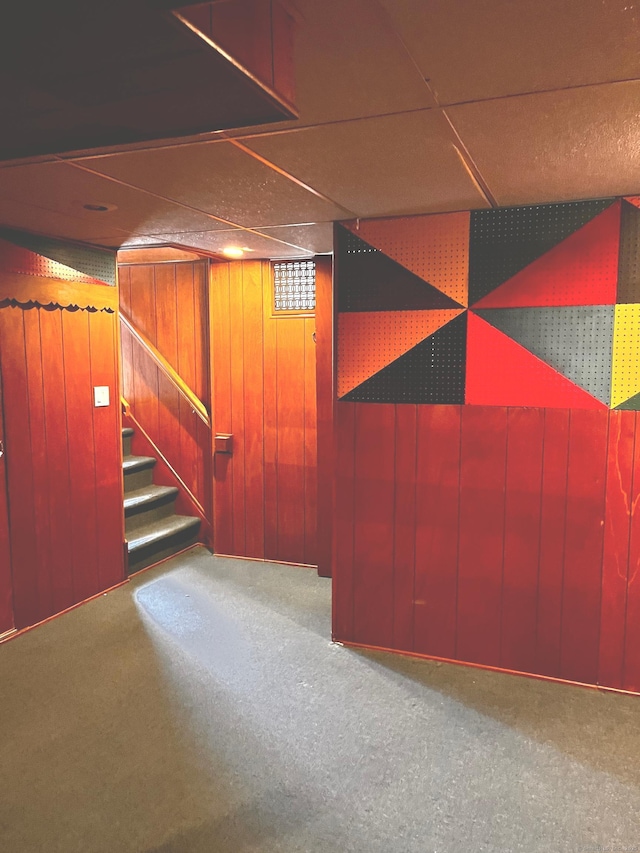 basement with carpet and wood walls