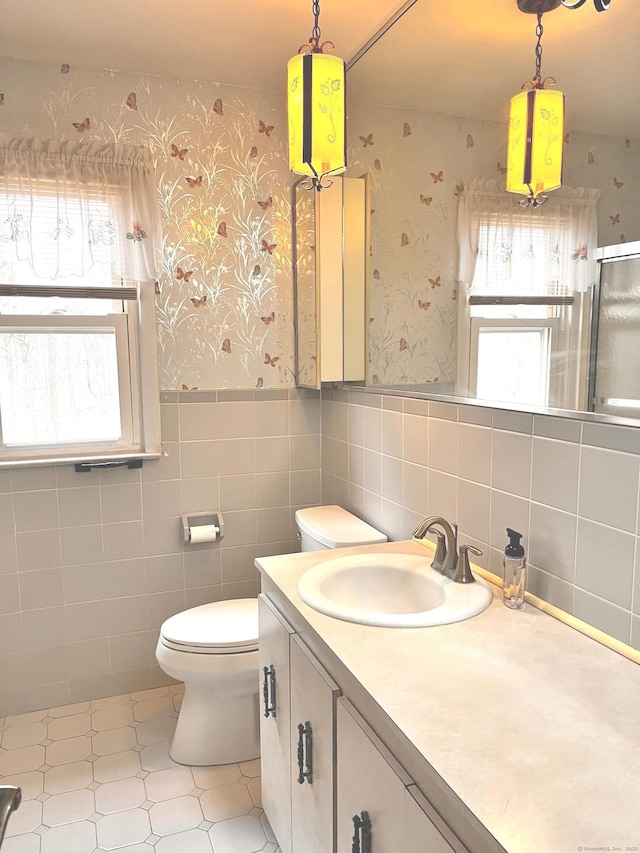 bathroom featuring vanity, plenty of natural light, tile walls, and toilet