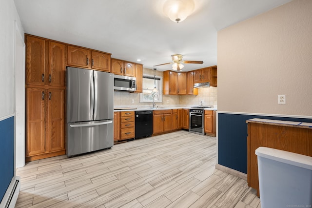 kitchen with sink, ceiling fan, baseboard heating, appliances with stainless steel finishes, and tasteful backsplash