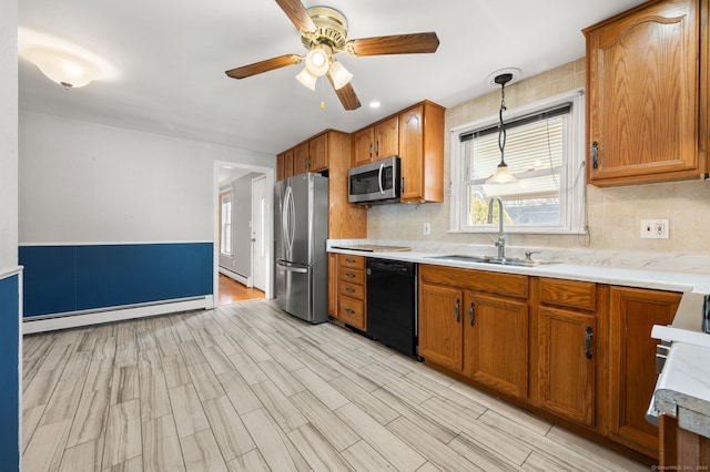 kitchen with appliances with stainless steel finishes, sink, baseboard heating, and decorative light fixtures