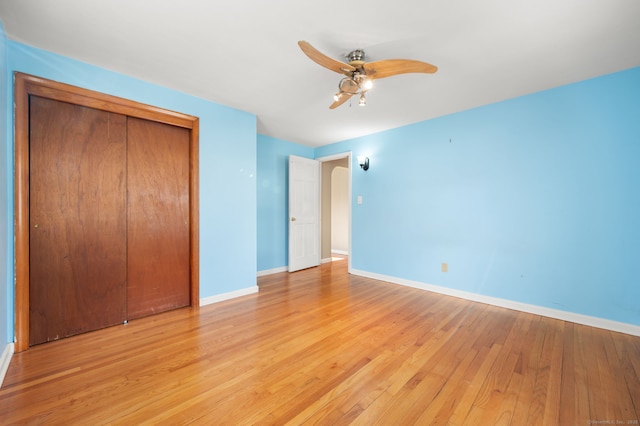 unfurnished bedroom with ceiling fan, a closet, and light wood-type flooring