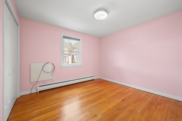 unfurnished room with baseboard heating and light hardwood / wood-style floors