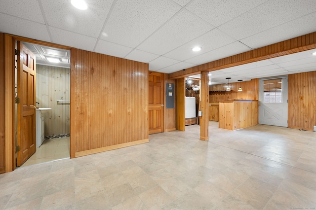 interior space featuring a paneled ceiling, electric panel, and wood walls