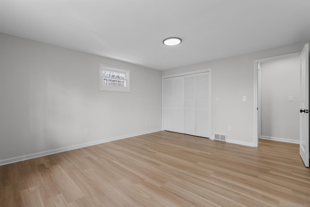 unfurnished bedroom featuring visible vents, baseboards, light wood-type flooring, and a closet