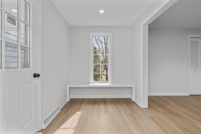 unfurnished room featuring light wood-type flooring, baseboards, and a baseboard radiator