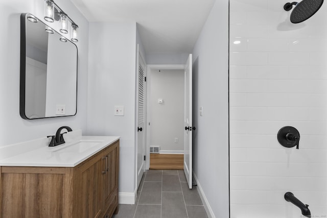 bathroom featuring tile patterned floors, baseboards, vanity, and a tile shower