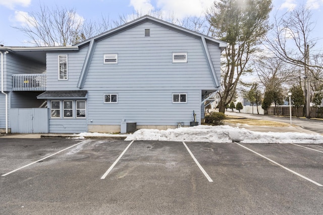 back of property featuring cooling unit, a balcony, and uncovered parking