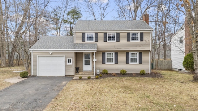 colonial home with a shingled roof, fence, aphalt driveway, a chimney, and an attached garage