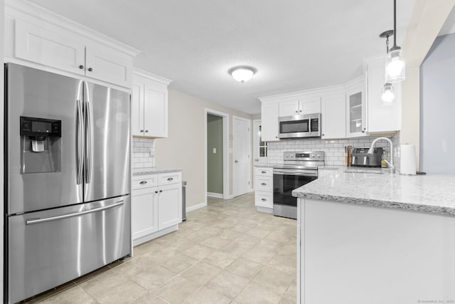 kitchen featuring a sink, backsplash, stainless steel appliances, white cabinets, and light stone countertops