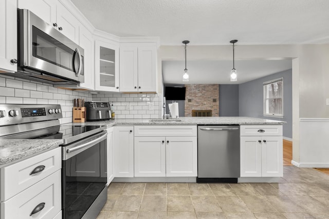 kitchen with a sink, white cabinetry, appliances with stainless steel finishes, a peninsula, and decorative backsplash