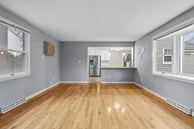 unfurnished living room with visible vents, baseboards, light wood-style floors, and a healthy amount of sunlight