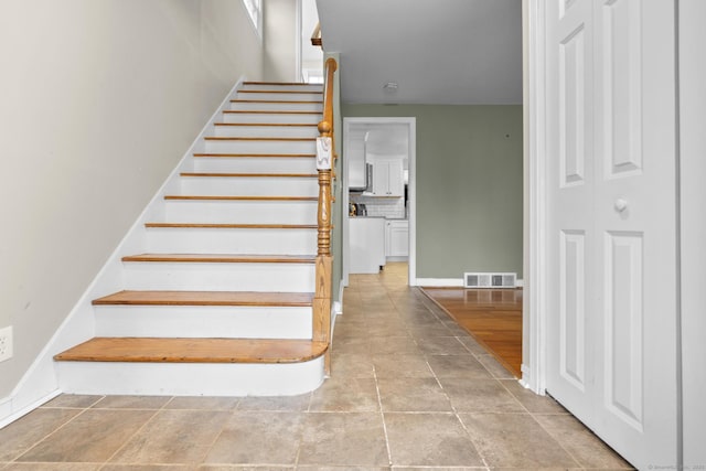 stairway featuring visible vents and baseboards