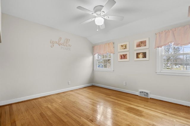 spare room featuring visible vents, baseboards, lofted ceiling, ceiling fan, and light wood-style floors