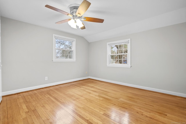 empty room featuring baseboards, a ceiling fan, light wood-style floors, and vaulted ceiling