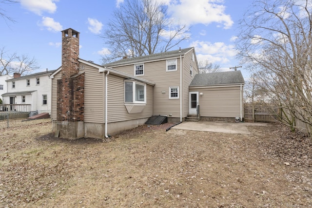 back of property featuring entry steps, a patio area, fence, and a chimney