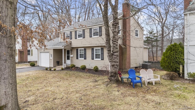 colonial inspired home featuring central AC, a shingled roof, a chimney, a garage, and aphalt driveway