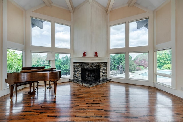 misc room with dark wood-type flooring, a fireplace, and high vaulted ceiling