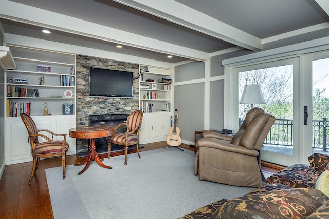 living room featuring beam ceiling, hardwood / wood-style flooring, and a fireplace