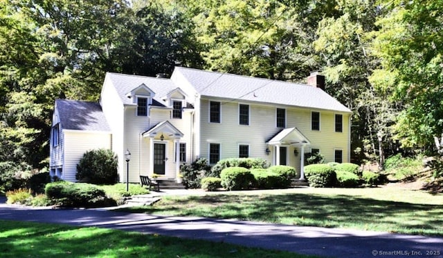 colonial-style house with a front yard and a chimney