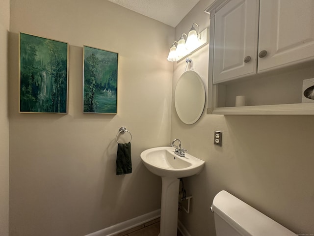 bathroom with tile patterned flooring, sink, a textured ceiling, and toilet