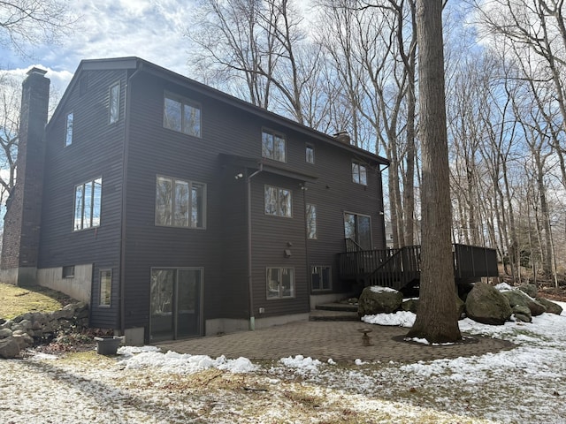 snow covered back of property with a deck