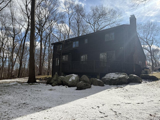 snow covered house featuring a wooden deck