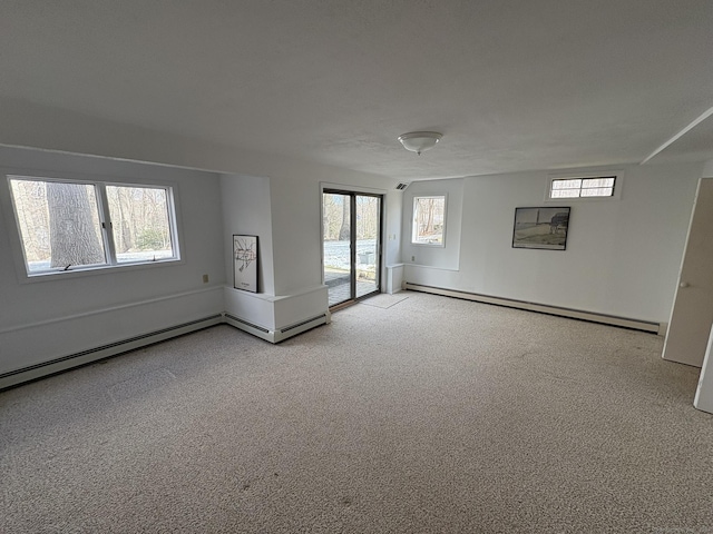 empty room with a wealth of natural light, light carpet, and a baseboard heating unit