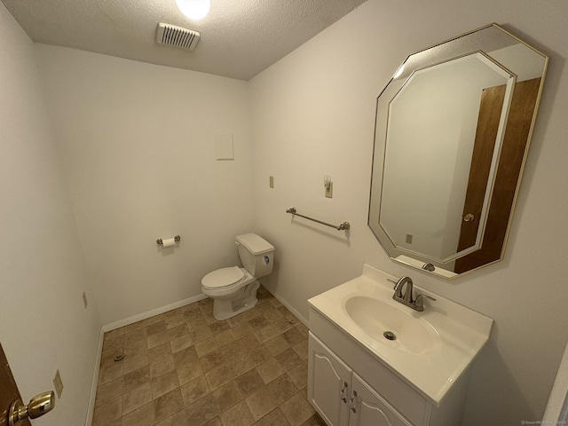 bathroom featuring vanity, a textured ceiling, and toilet