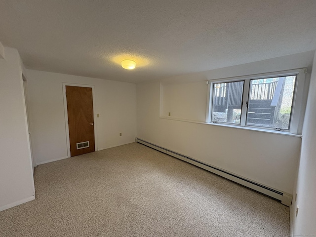 carpeted spare room with a textured ceiling and baseboard heating