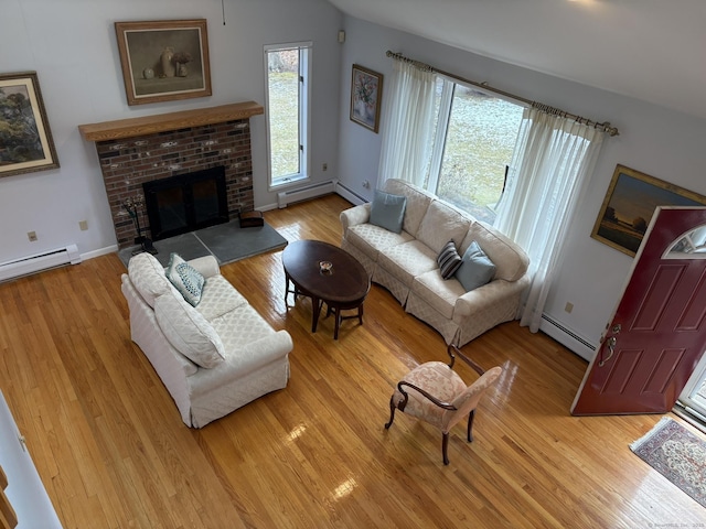 living room featuring a baseboard heating unit, wood-type flooring, and a brick fireplace