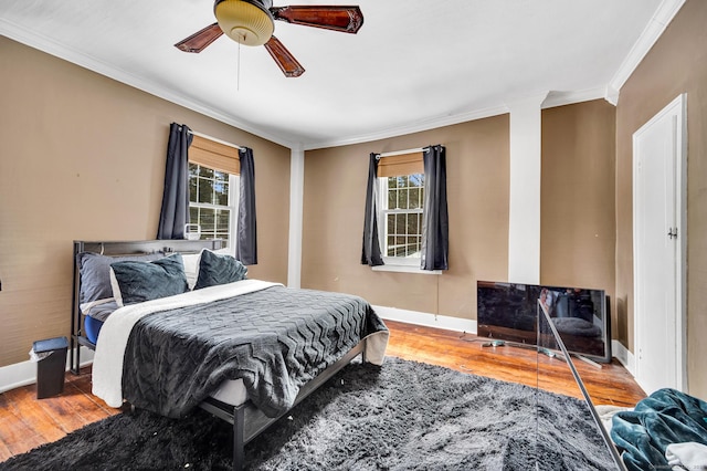 bedroom featuring multiple windows, wood-type flooring, ornamental molding, and ceiling fan