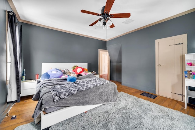 bedroom with hardwood / wood-style flooring, ceiling fan, and ornamental molding