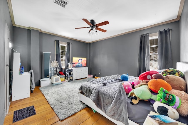 bedroom featuring hardwood / wood-style flooring, ornamental molding, and ceiling fan