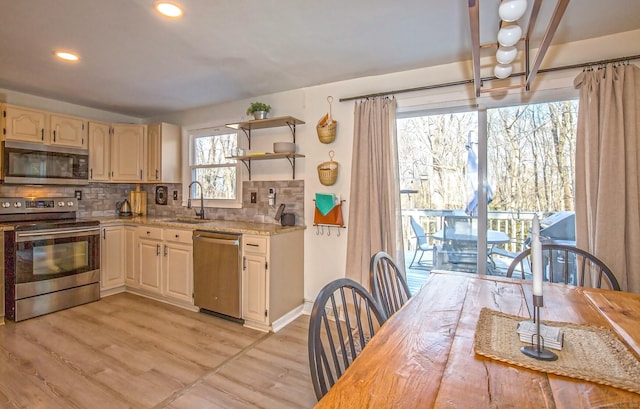 kitchen featuring appliances with stainless steel finishes, light hardwood / wood-style floors, sink, and decorative backsplash