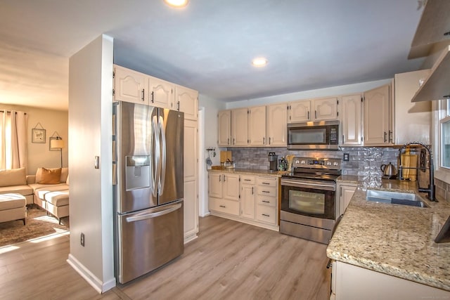 kitchen with appliances with stainless steel finishes, light stone countertops, sink, and backsplash