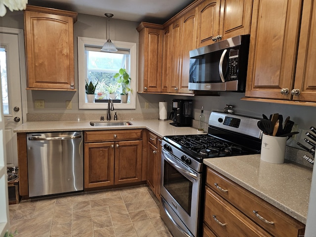 kitchen featuring appliances with stainless steel finishes, decorative light fixtures, light stone countertops, and sink